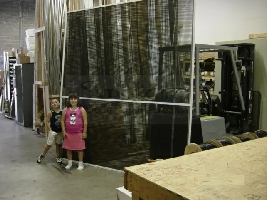 Two children standing beside a large Simplicity screen panel in the workshop