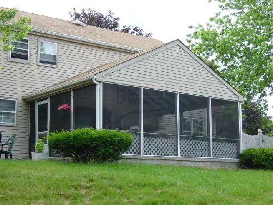 A long screened porch running across the gable end of a clapboard house