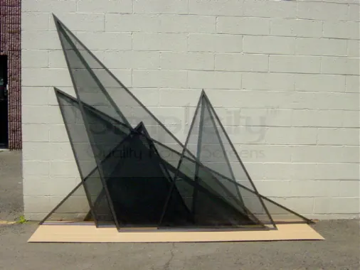 Finished triangular screen panels leaning against a block wall outside the workshop