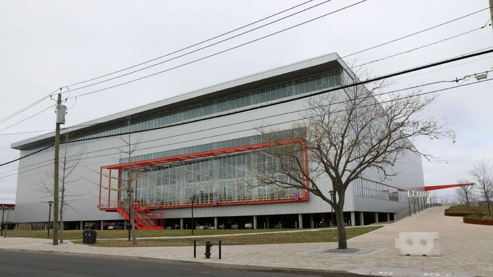 A long civic building with a red-framed screened structure running along its frontage