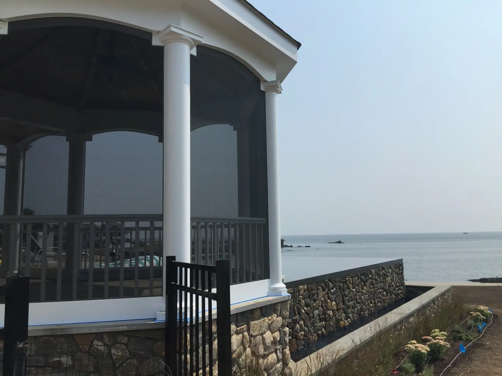 Looking out to open water from inside a screened porch with white columns