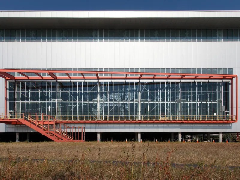A red-framed screened structure spanning the length of a low commercial building