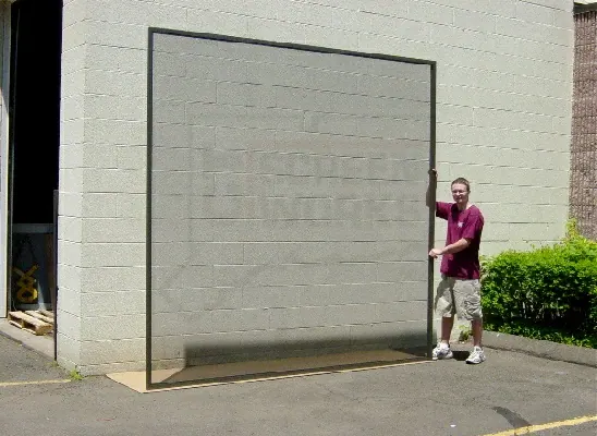 A man standing beside a Screen Wall panel taller than he is, showing the scale it can be built to